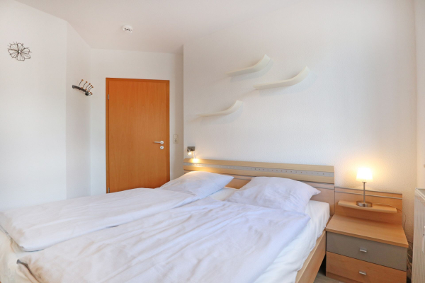 Blick in das Schlafzimmer mit einem Doppelbett und einem Nachttisch mit Lampe