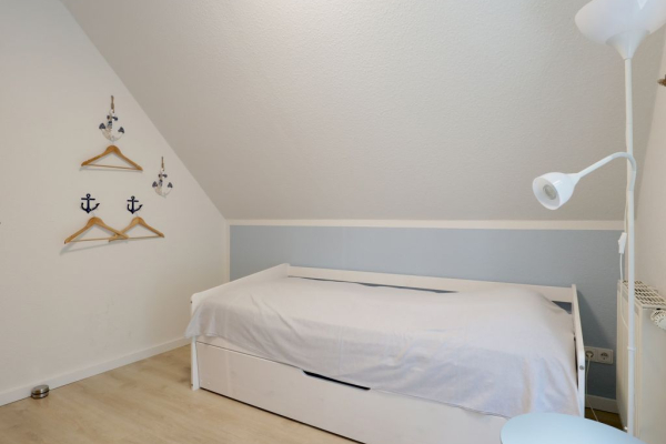 Blick in das Schlafzimmer mit einem Einzelbett und einem weiteren TV