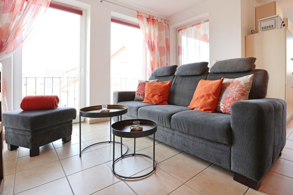 Blick auf das graue Sofa, einen Hocker und 2 kleine Tische
