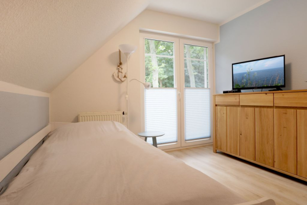 Blick in das Schlafzimmer mit einem Einzelbett und einem weiteren TV