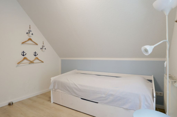 Blick in das Schlafzimmer mit einem Einzelbett und einem weiteren TV