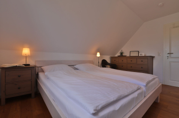 Ruhe-Insel Ferienhaus - Blick in dass Schlafzimmer mit einem Doppelbett im OG