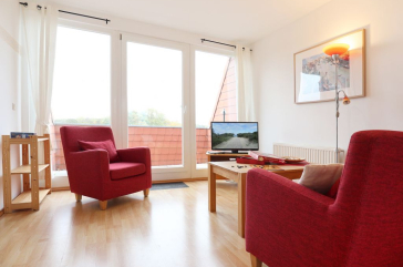 Blick auf den offenen Wohnbereich mit Sessel, Sofa und Fernseher