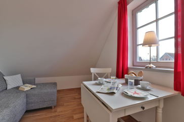 graues Ecksofa, Esstisch mit weißen Stühlen und ein Fenster