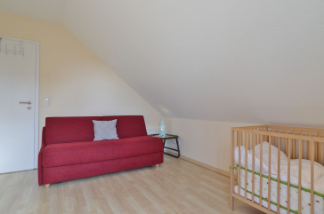 Strandgut Ferienhaus - Blick in das Gästezimmer mit Babybett und Wickeltisch