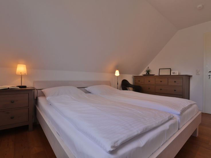 Ruhe-Insel Ferienhaus - Blick in dass Schlafzimmer mit einem Doppelbett im OG