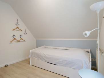 Blick in das Schlafzimmer mit einem Einzelbett und einem weiteren TV