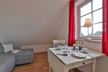 graues Ecksofa, Esstisch mit weißen Stühlen und ein Fenster