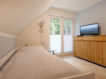 Blick in das Schlafzimmer mit einem Einzelbett und einem weiteren TV