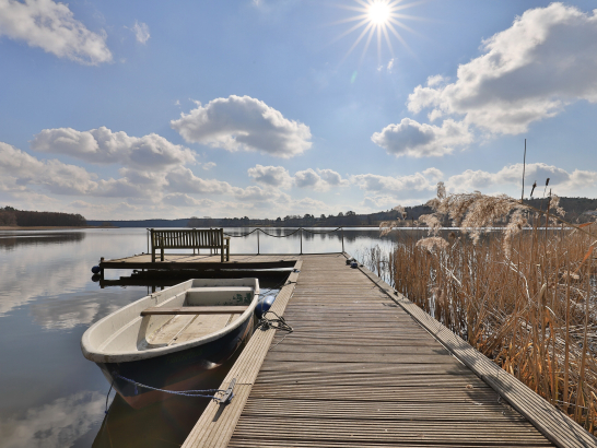 Ein Boot liegt am Steg. Im Hintergrund der See.