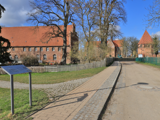 Eine Straße führt an Backsteinhäusern vorbei zu einer Kirche. 