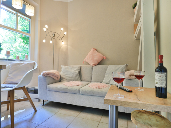 Heller Wohnbereich mit Sofa und Beisteltisch und Fenster mit Blick in den Garten